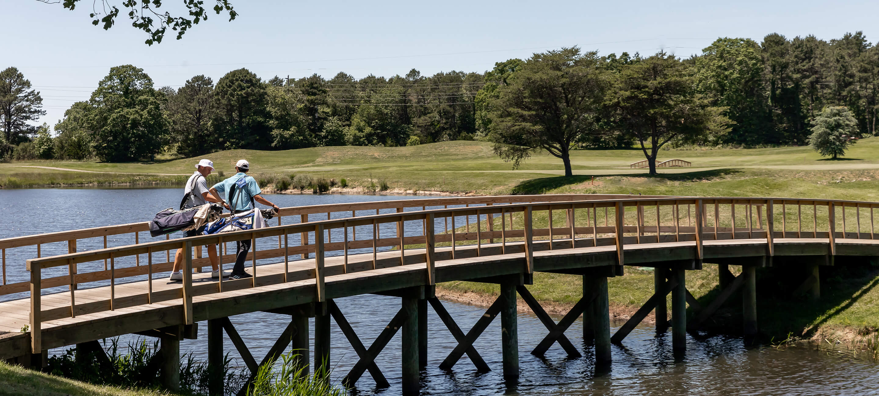 golfers walking across wooden bridge