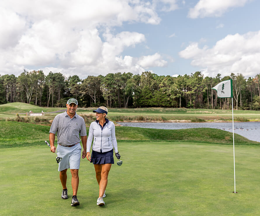 Man and woman golfers walking toward the camera on the 7th hole green
